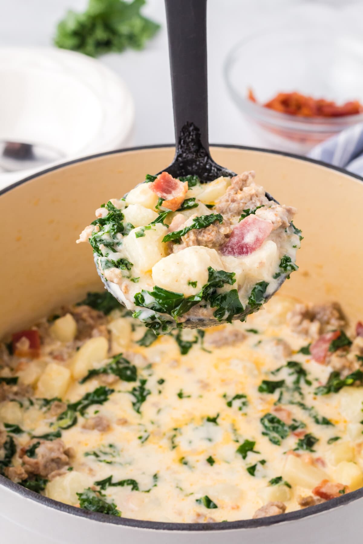 zuppa toscana soup in ladle with pot of soup