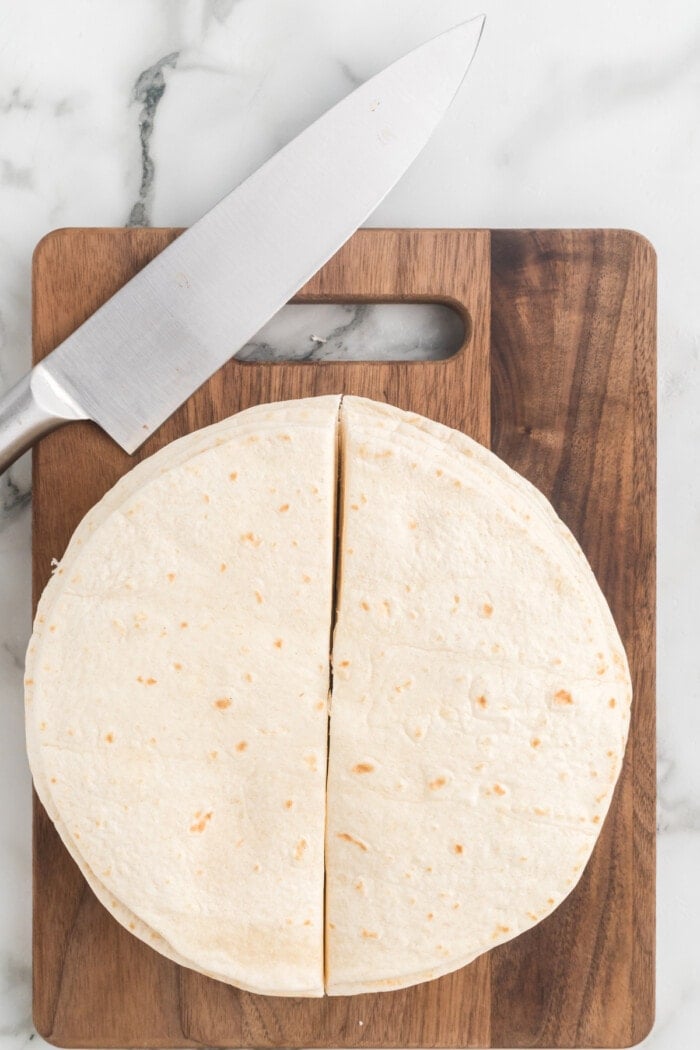 Flour tortillas cut in half on a cutting board
