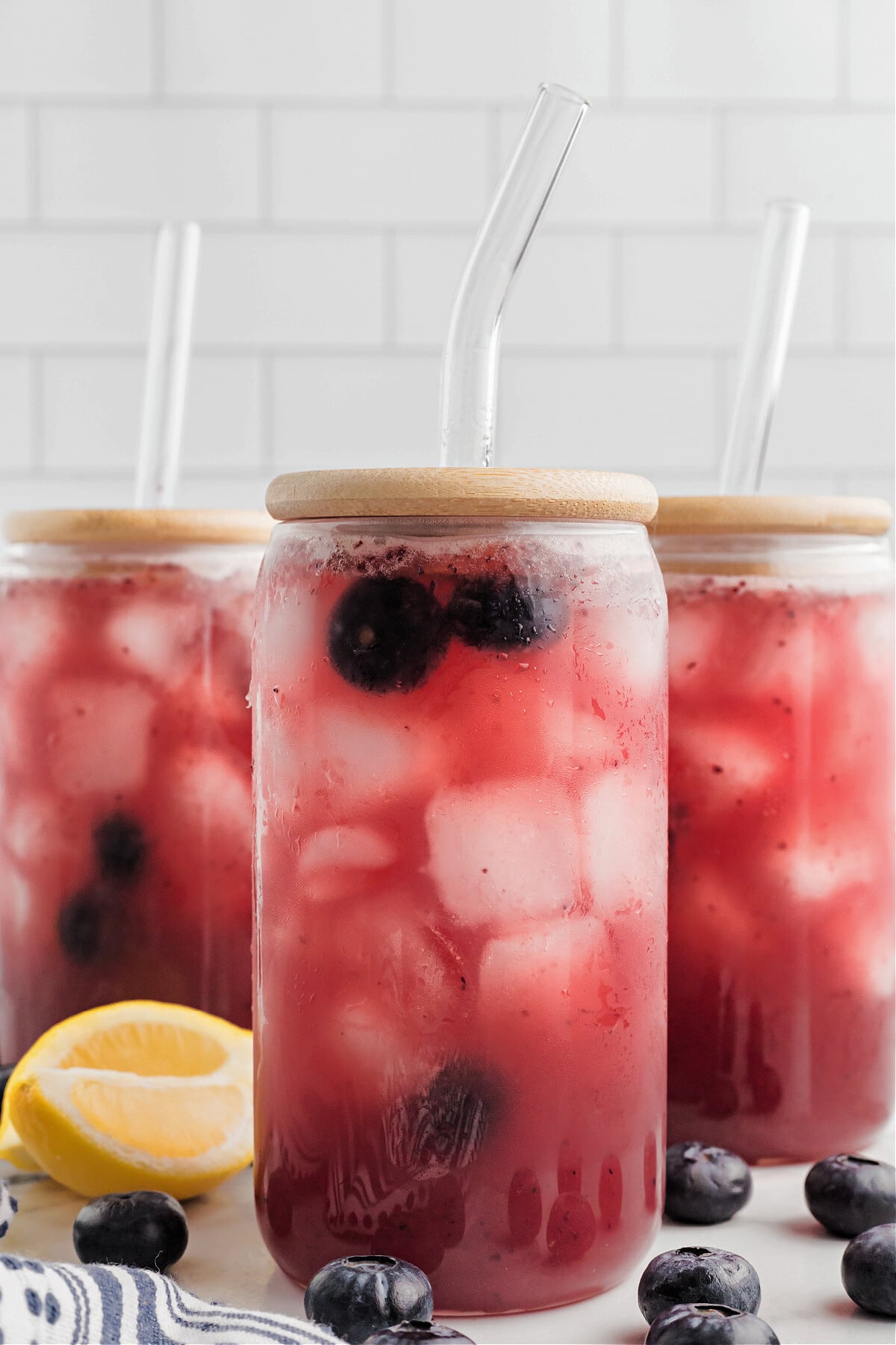blueberry lemonade in glasses with lids and clear straws