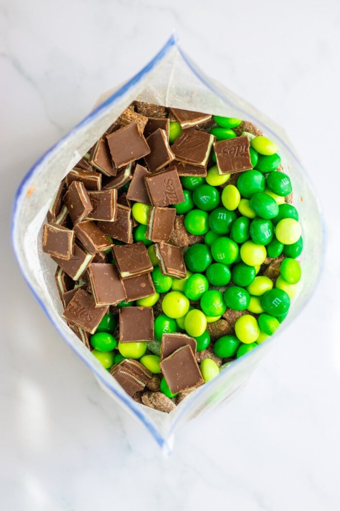 Adding the m&ms and mints into the Mint Chocolate Muddy Buddies.