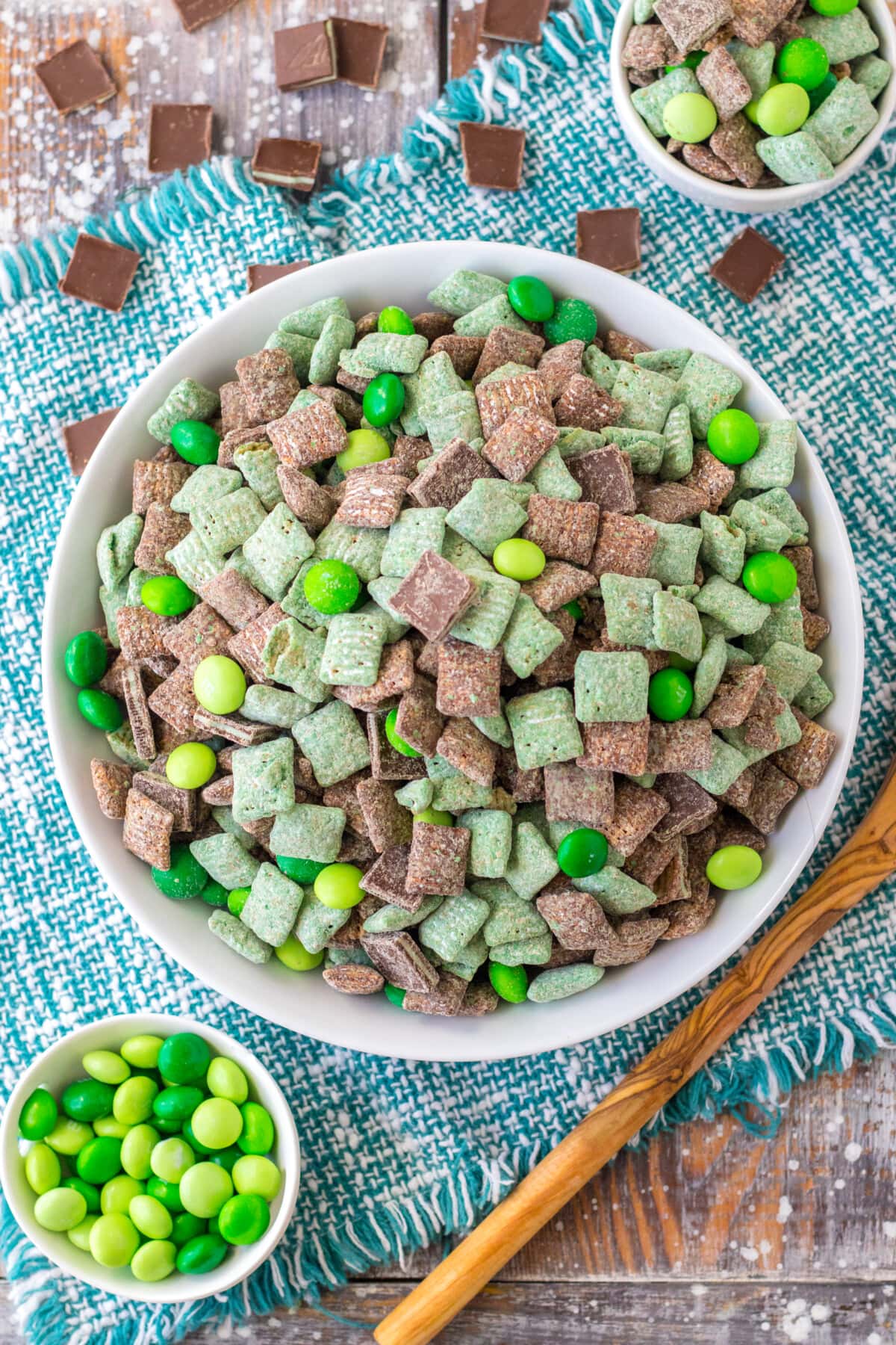 These Mint Muddy Buddies are made with Chex cereal, chocolate, Andes mints, and M&M's for a delicious treat that's perfect for St. Patrick's Day! Mint Chocolate Muddy Buddies in a white bowl.