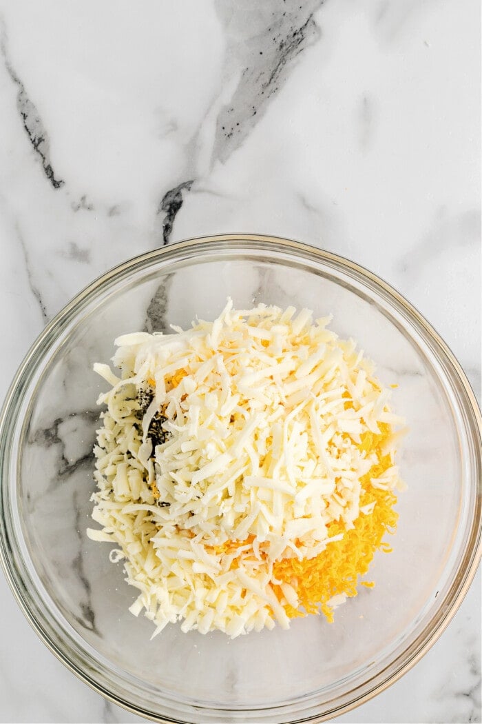 cheese with other ingredients in glass bowl to make pizza dip
