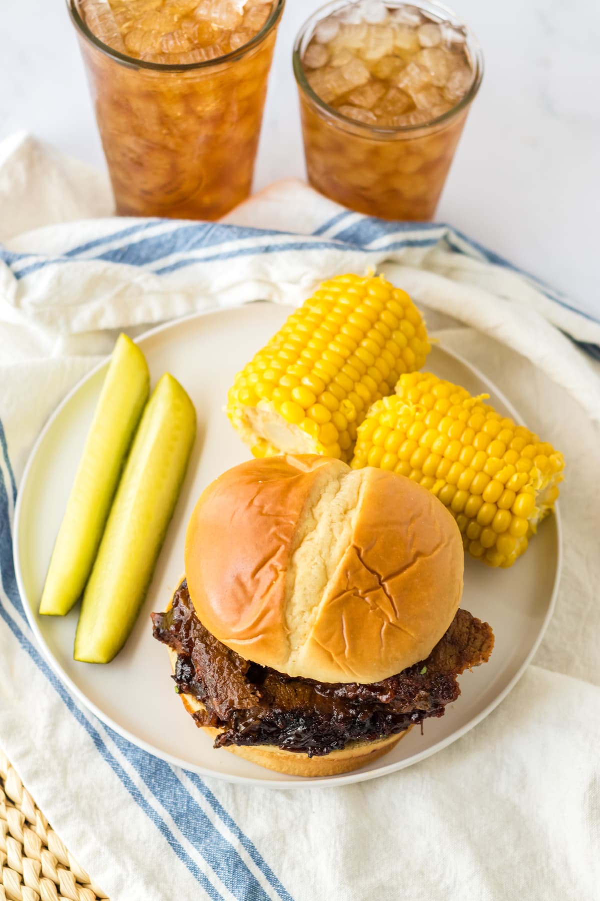 Overhead view of a slow cooker beef brisket sandwich with corn and a pickle
