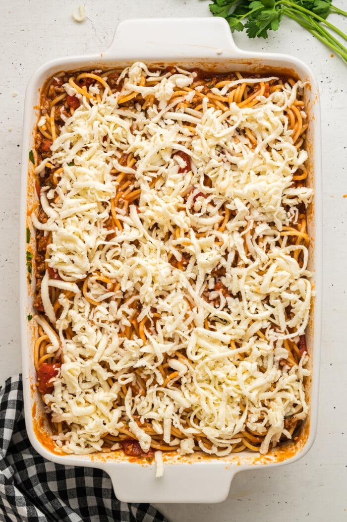 Spaghetti topped with cheese in a casserole dish