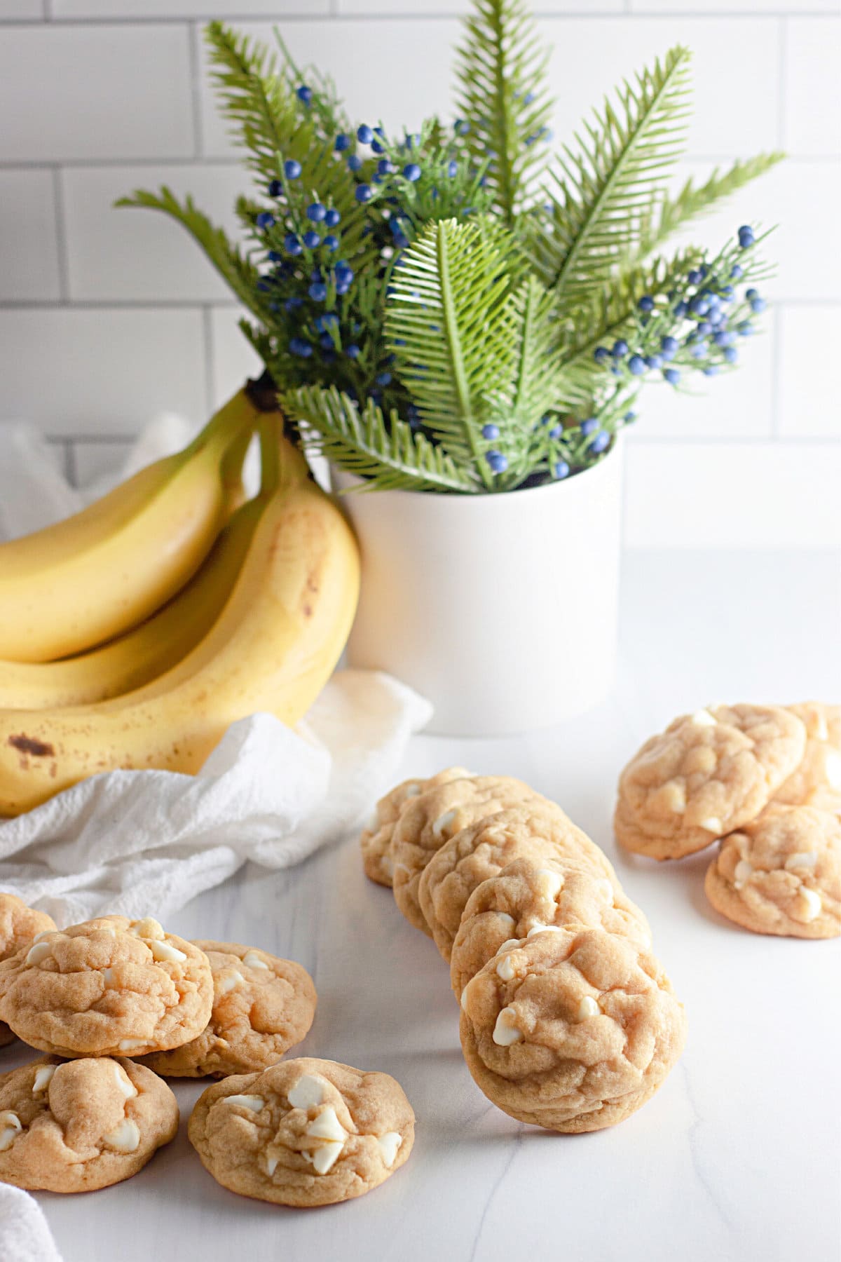Banana cookies on the counter top in front of bananas and a plant