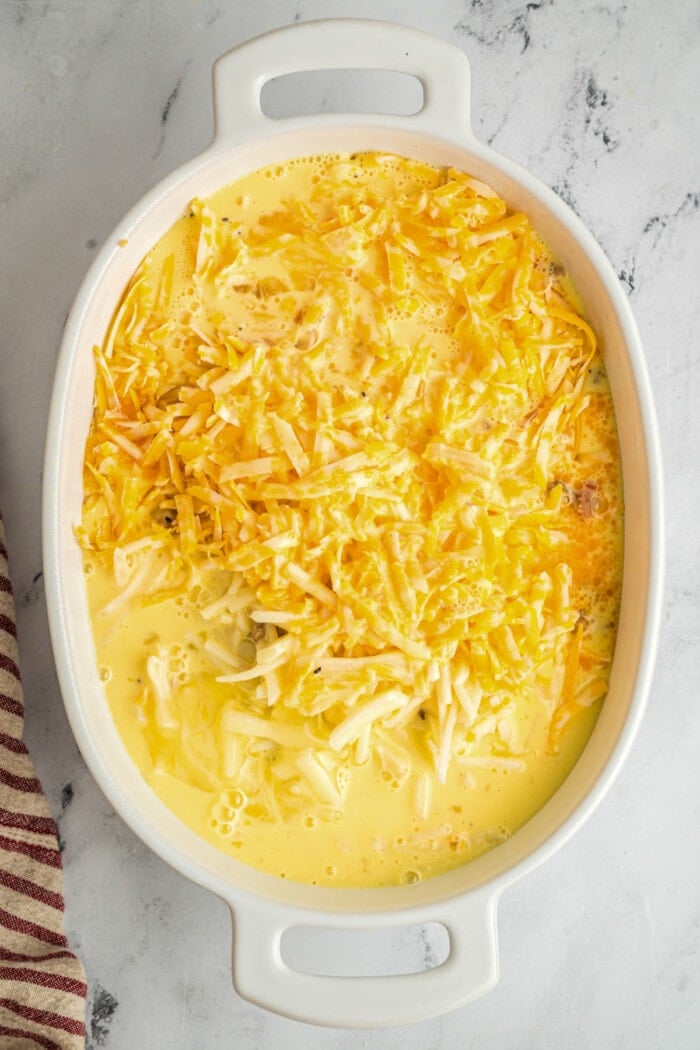 white casserole dish with eggs, hash browns, cheese and cooked sausage