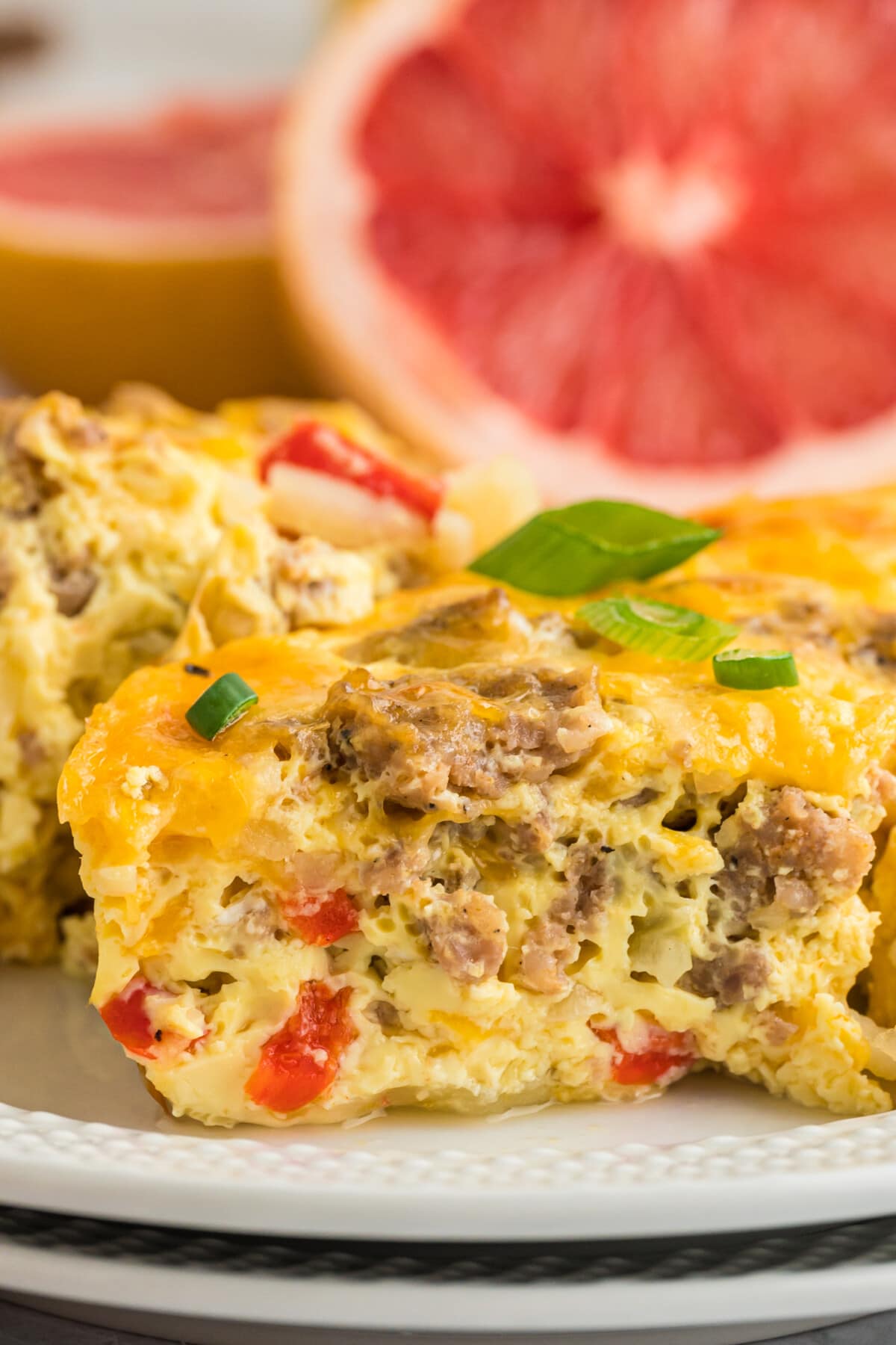 slice of breakfast casserole on a plate with grapefruit. 