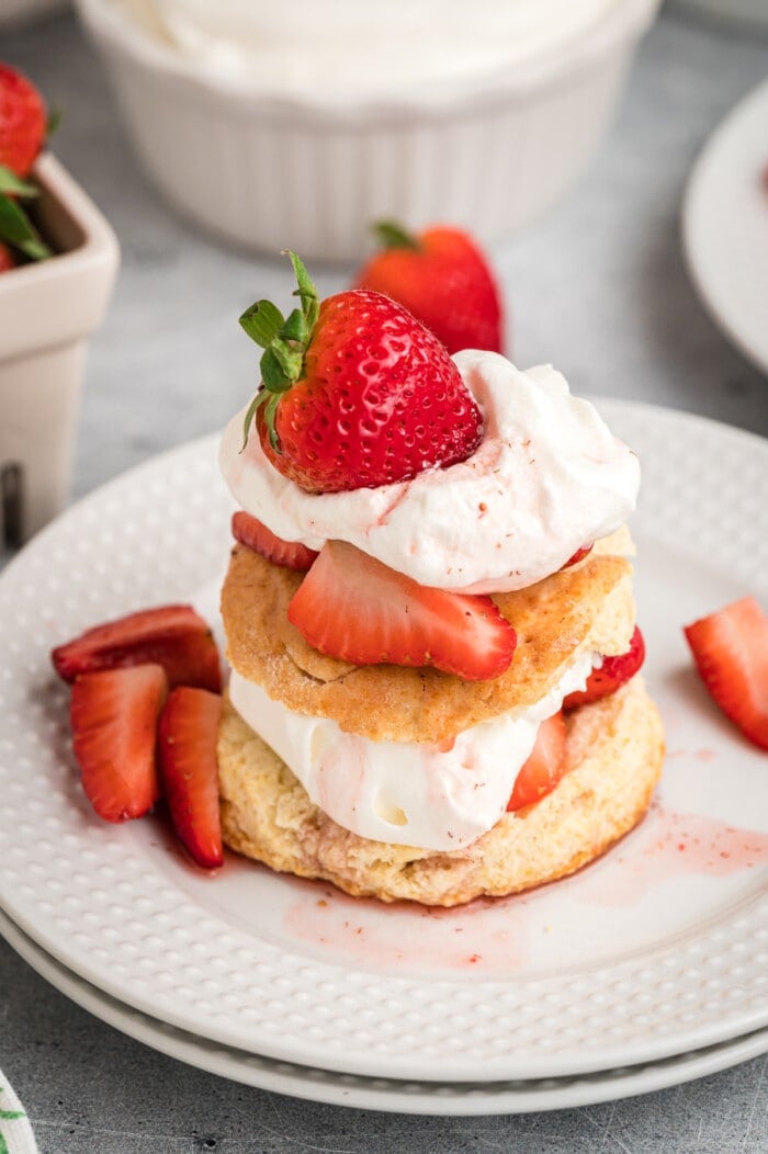 Strawberry shortcake topped with more strawberries on a white plate