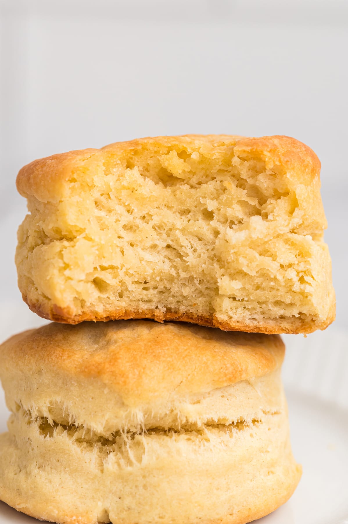 A stack of two biscuits, one with a bite missing ot show the fluffy insides