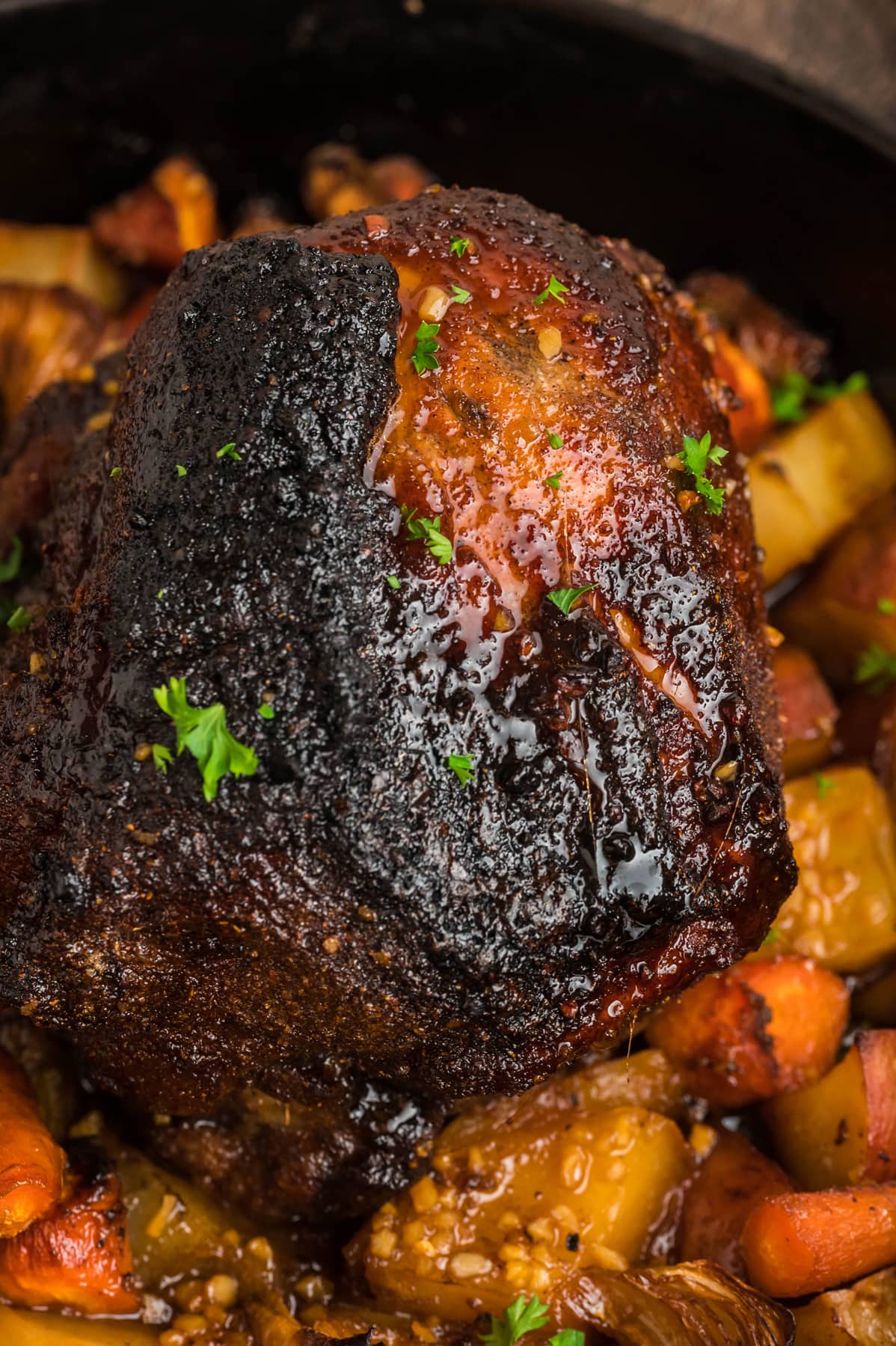 Overhead view of a pork shoulder roasted in a skillet with vegetables