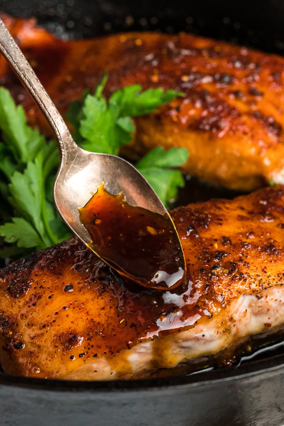 A spoon drizzling honey glaze over salmon