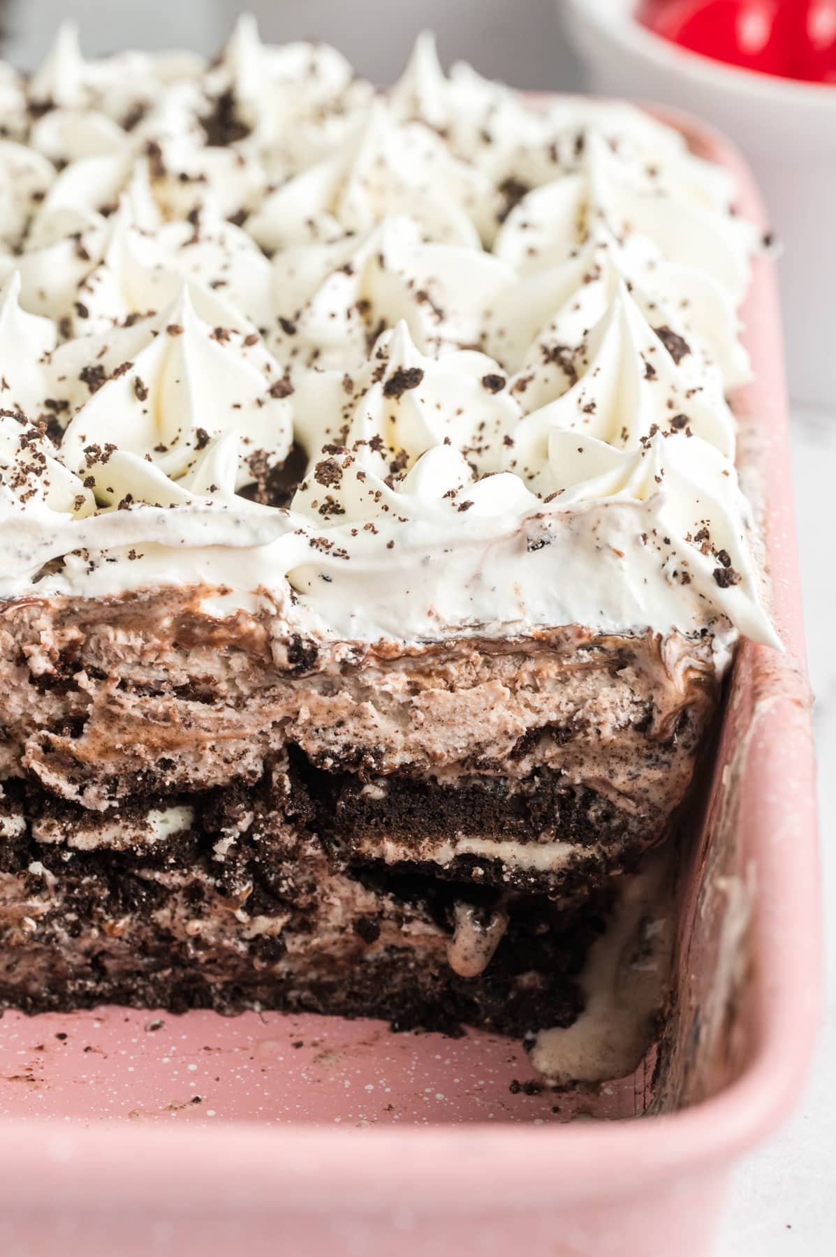 An Oreo ice cream cake in a pan with a slice missing to show the layers