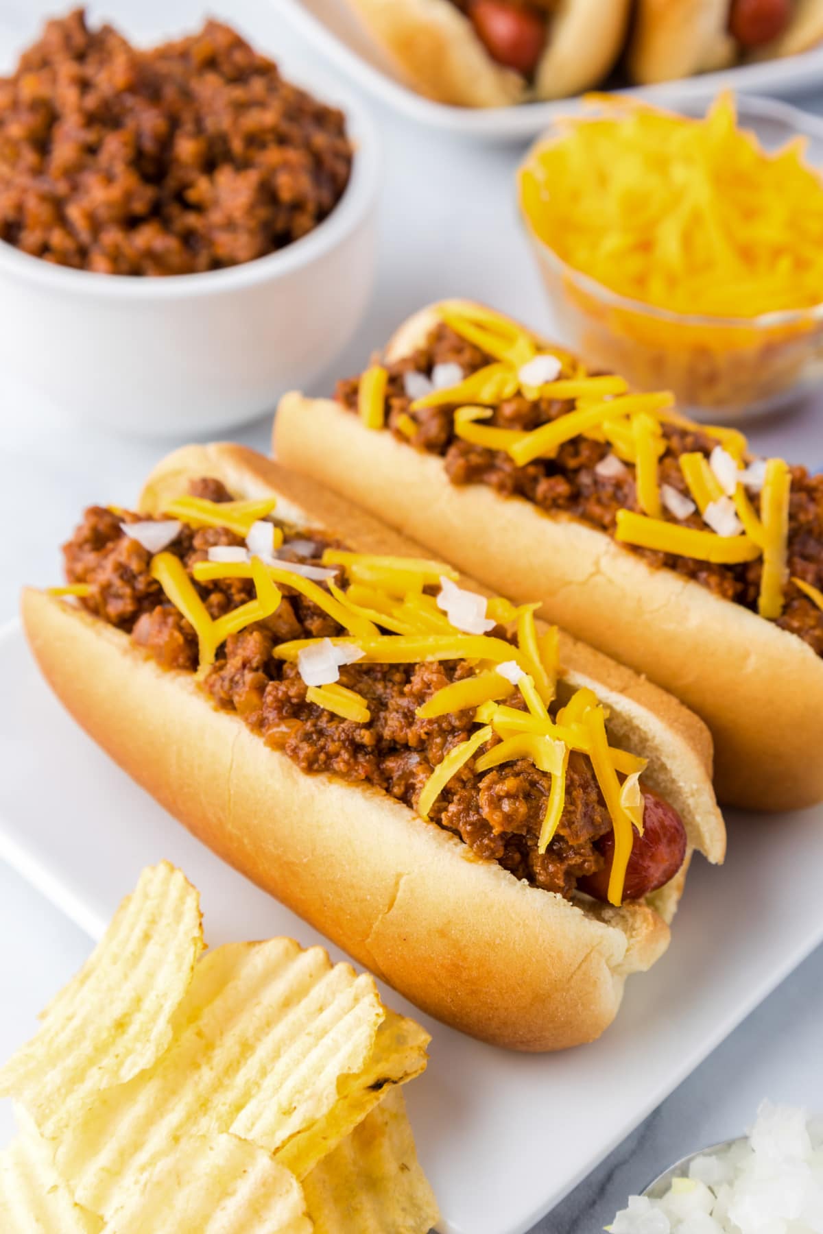 hot dogs in buns with chili, cheese and onions