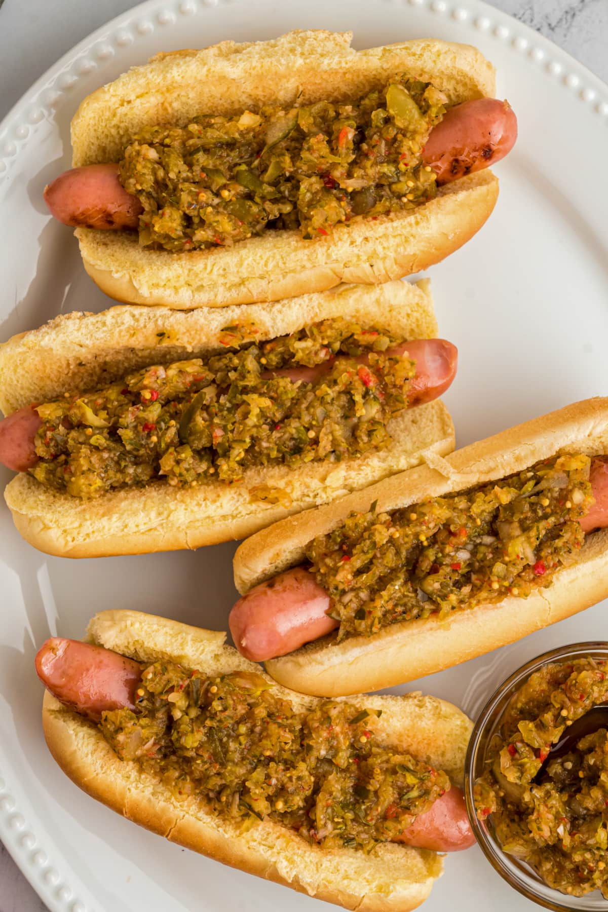 hot dogs on white platter with relish