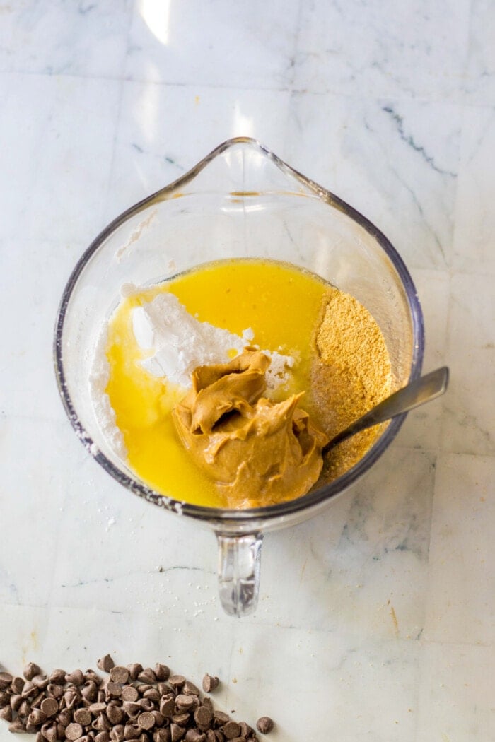 crushed graham crackers, butter, powdered sugar and peanut butter in clear glass mixing bowl