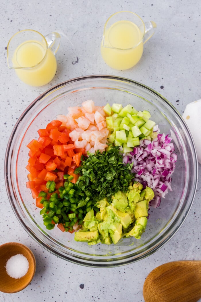 shrimp with red onions, jalapeno peppers, cucumber, tomatoes, avocado and cilantro in glass bowl