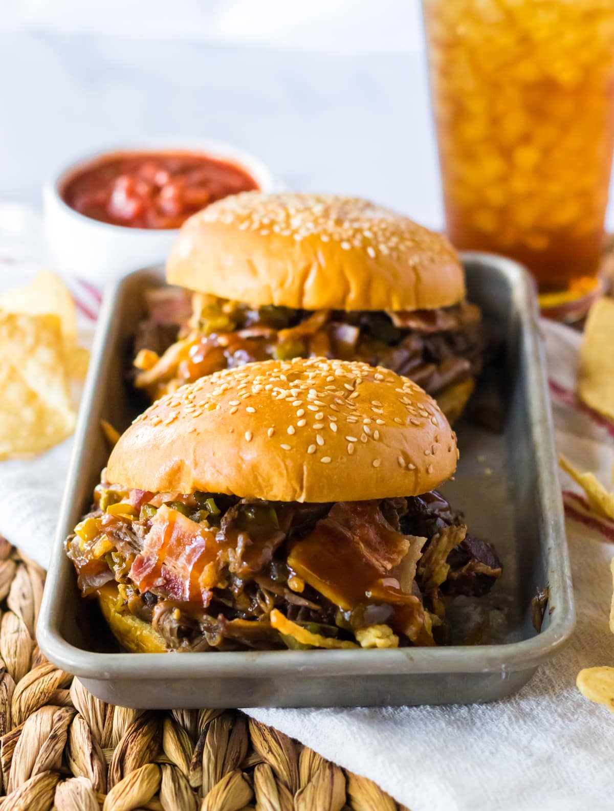 bbq beef sandwiches with sauce and bacon on metal tray