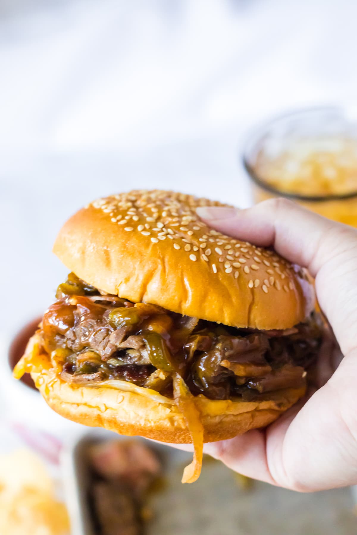 hand holding bbq beef sandwich with onions