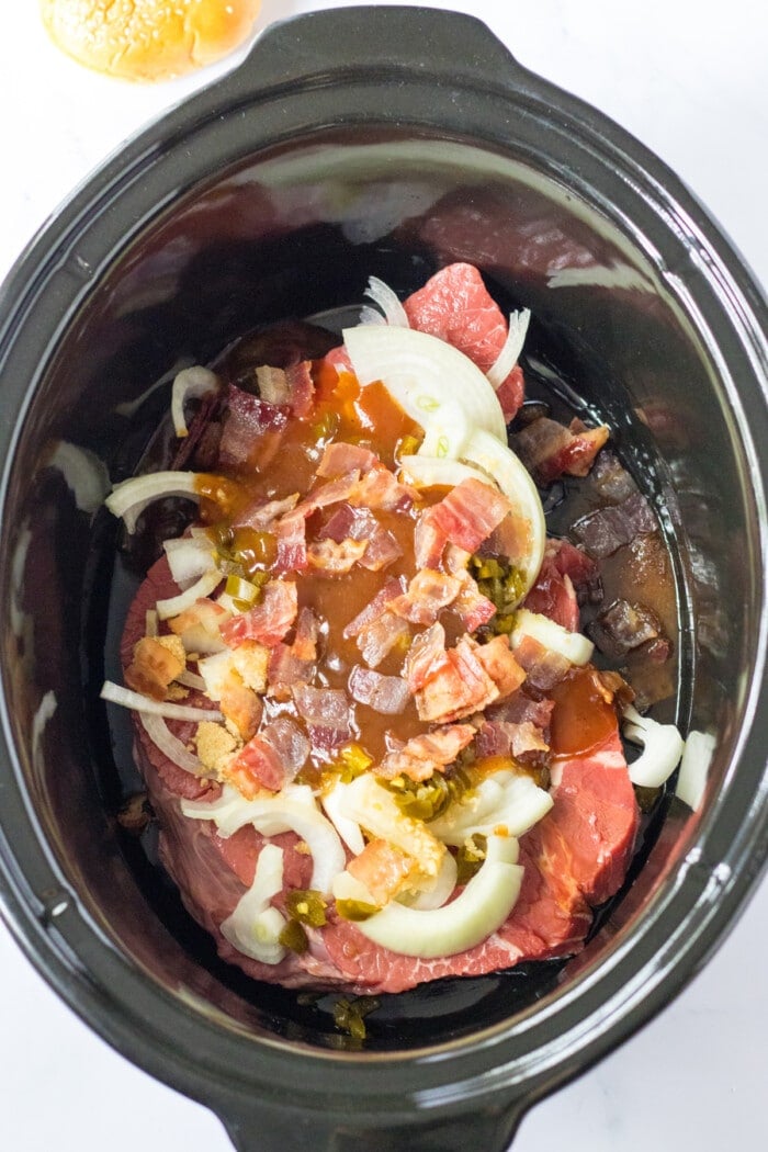 chuck roast in slow cooker with onions, bacon and beef broth