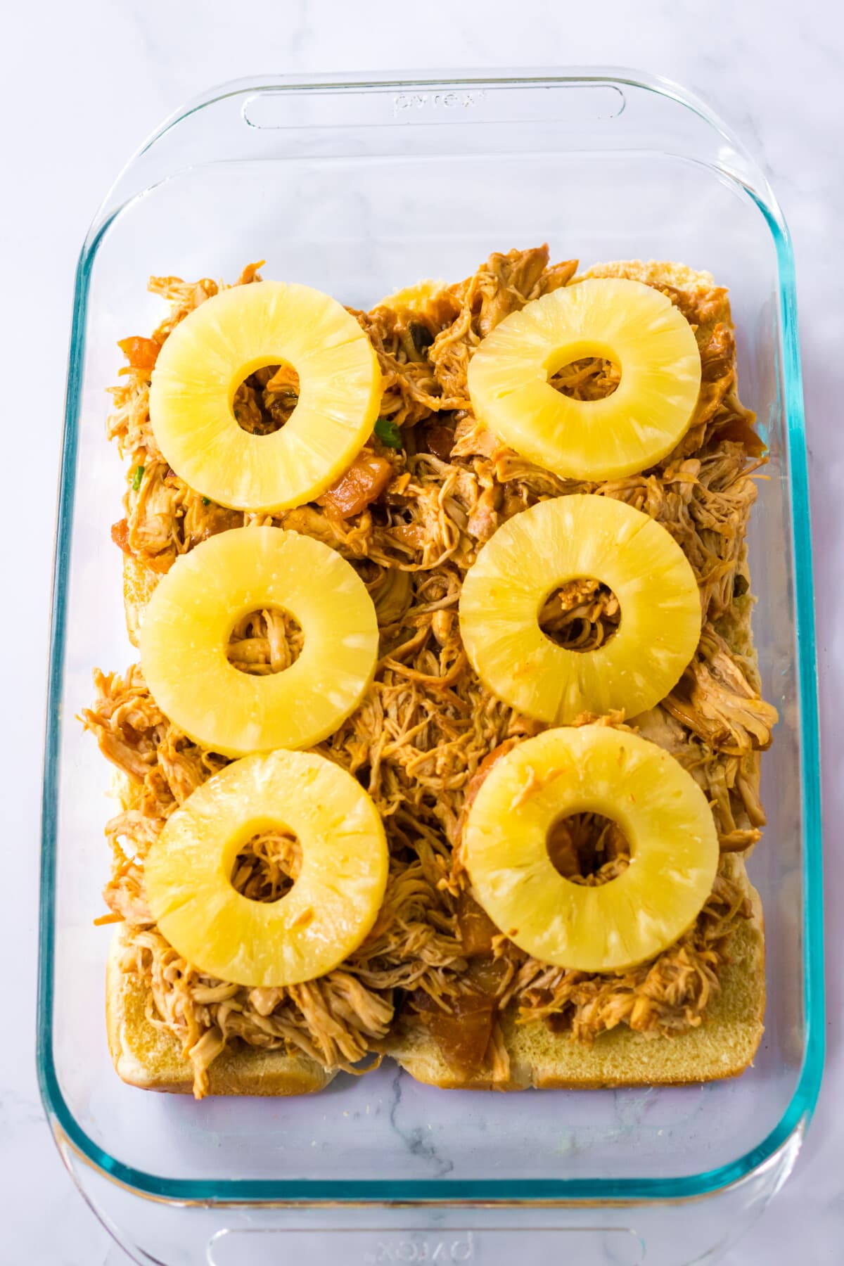 barbecue chicken in a pan with sliced pineapple on top