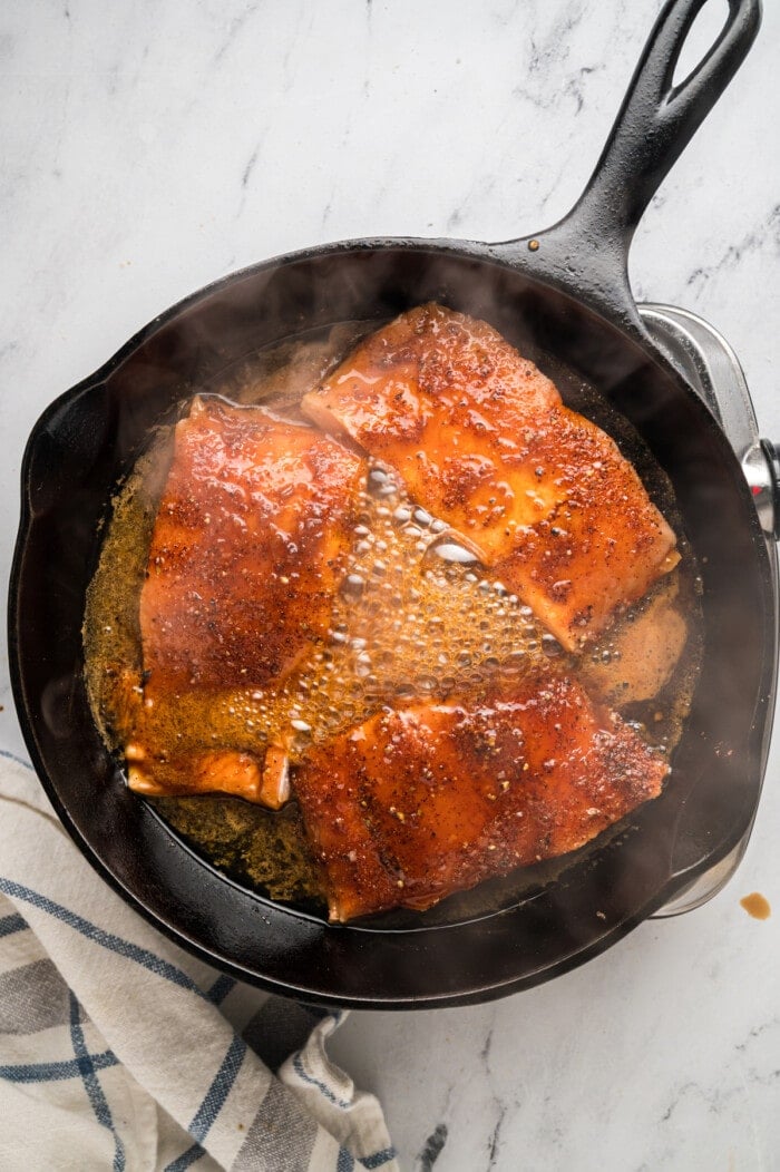 Honey glazed salmon cooking in a skillet
