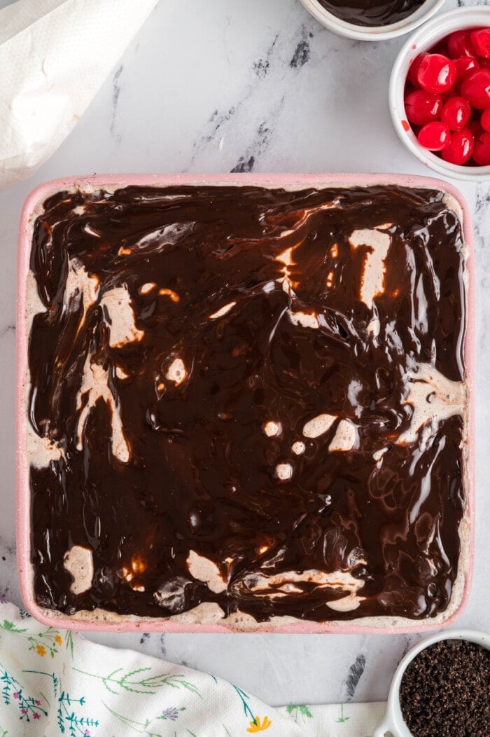 Hot fudge being spread over an ice cream cake