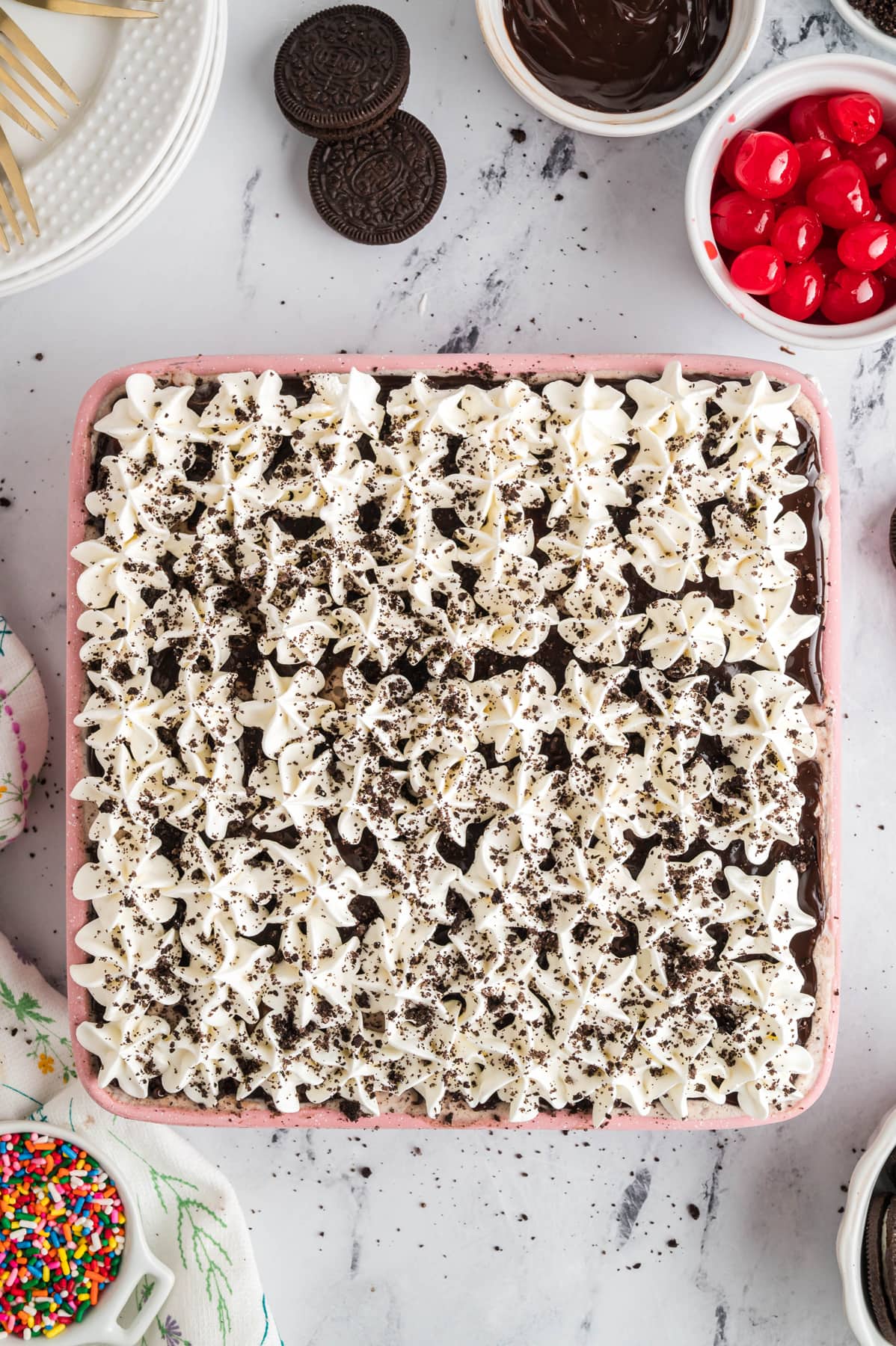 Ice cream cake topped with dollops of whipped topping and oreo crumbs