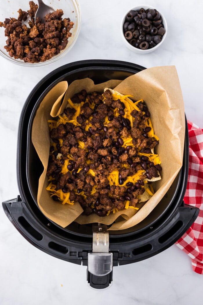 ground beef on top of tortilla chips and cheese in air fryer for nachos