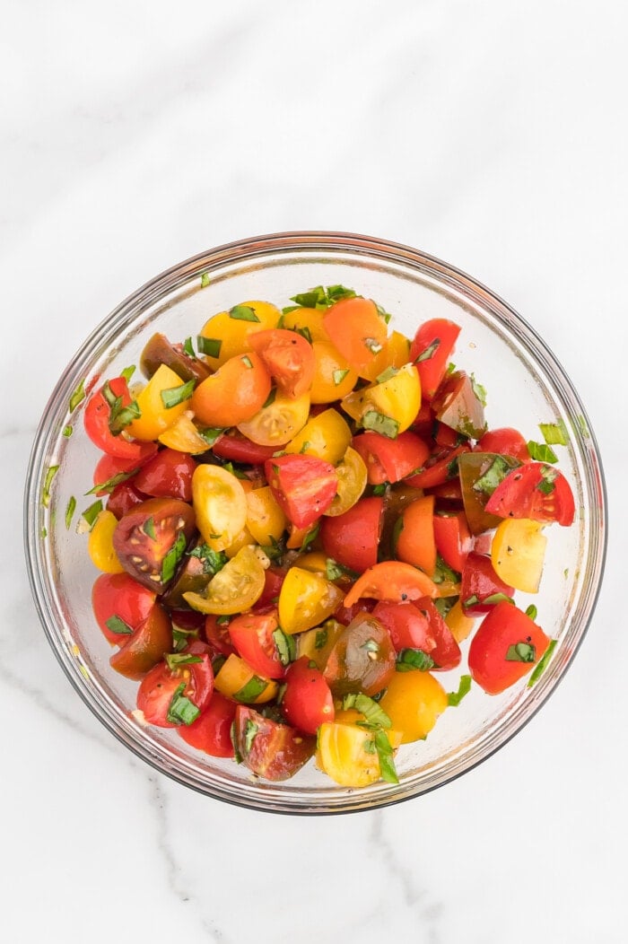 tomatoes, basil and garlic mixed in glass bowl