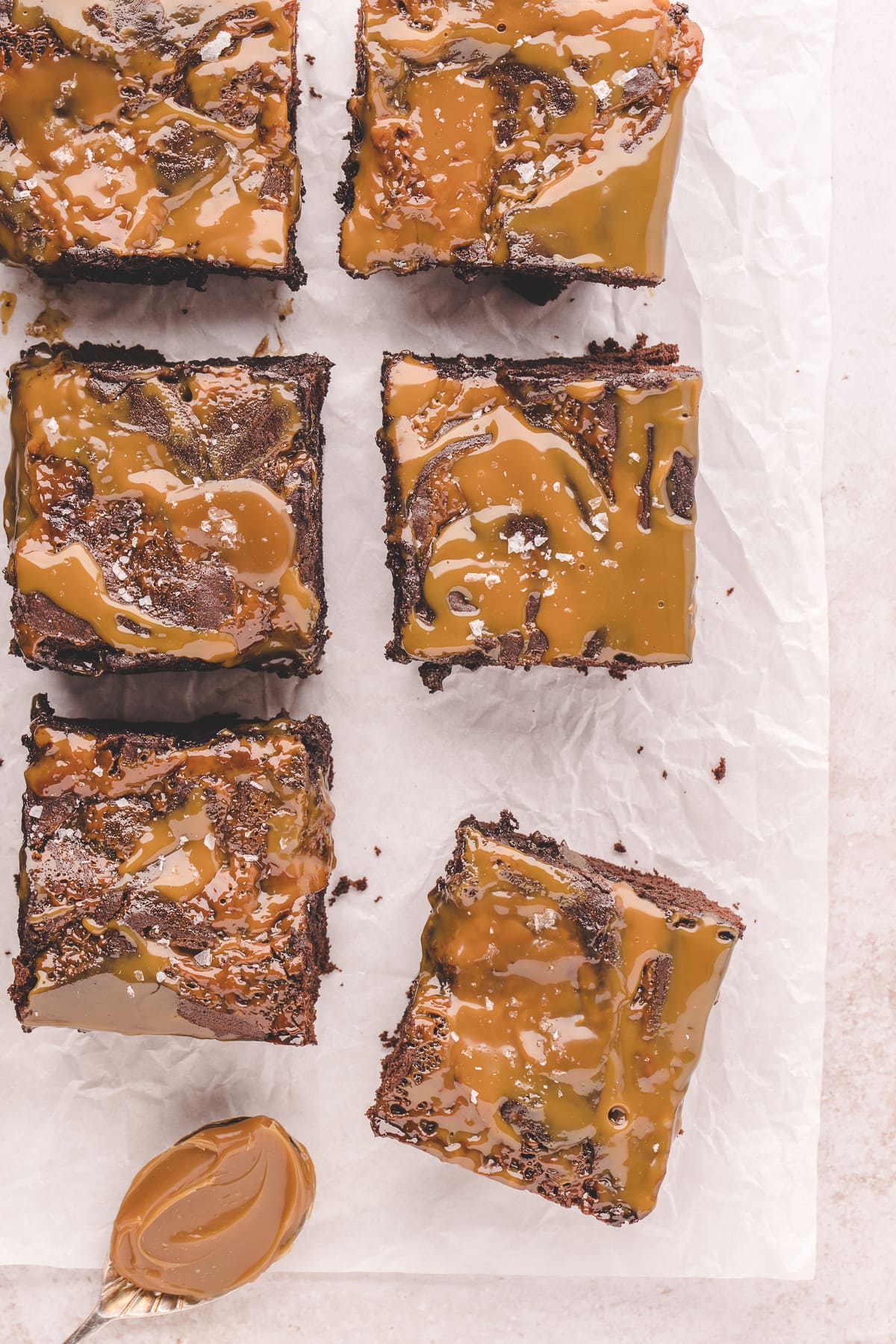 caramel brownies cut into squares on parchment paper