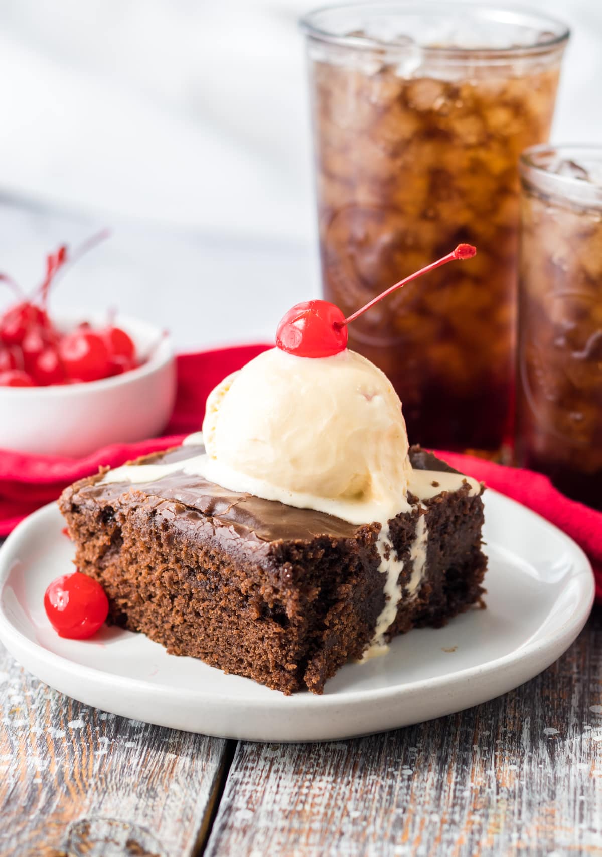 coca cola cake on white plate with ice cream and cherry on top