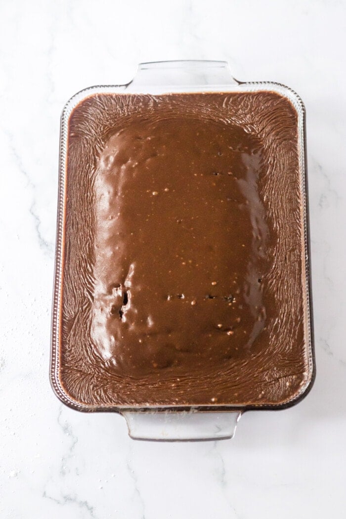 frosting on top of coca cola cake in glass baking dish