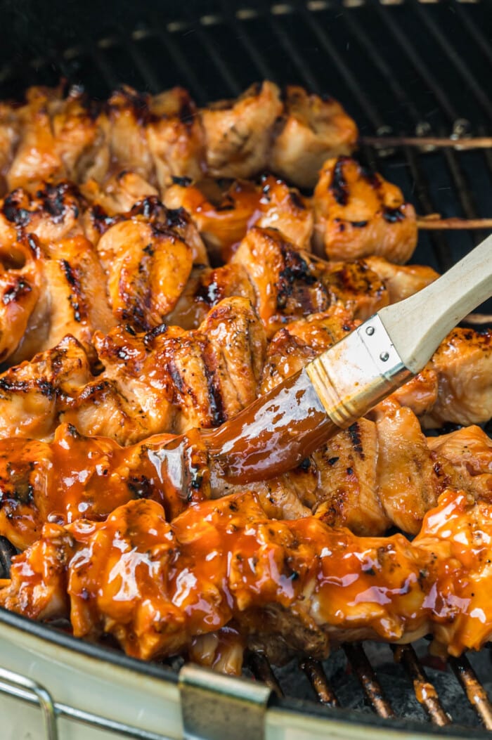 Chicken kabobs being basted with sauce