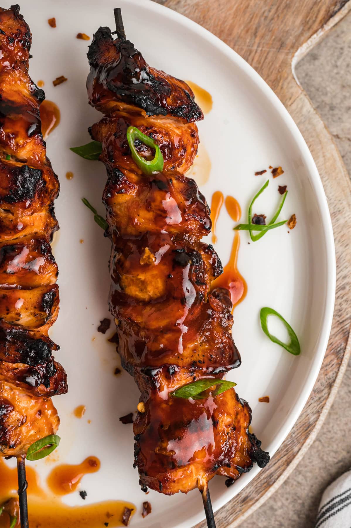 Chicken skewers on a plate topped with green onion