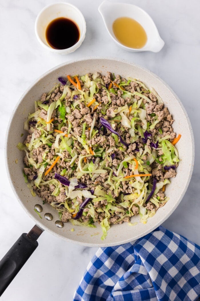 ground pork cooked in skillet with coleslaw mix