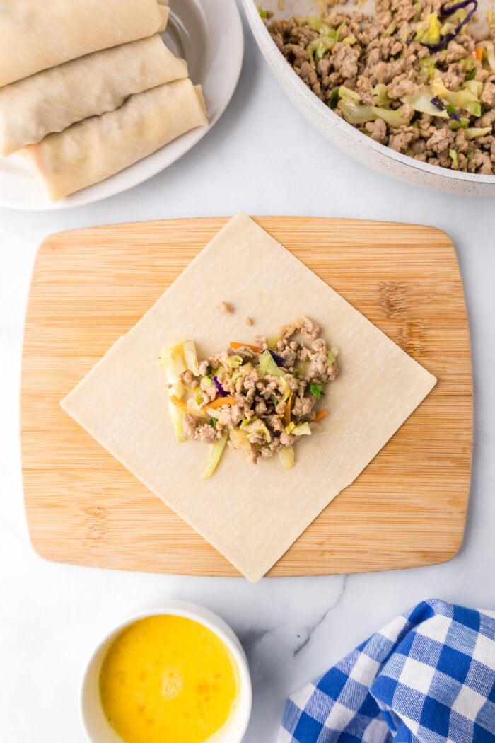 wonton wrapper on cutting board with egg roll filling