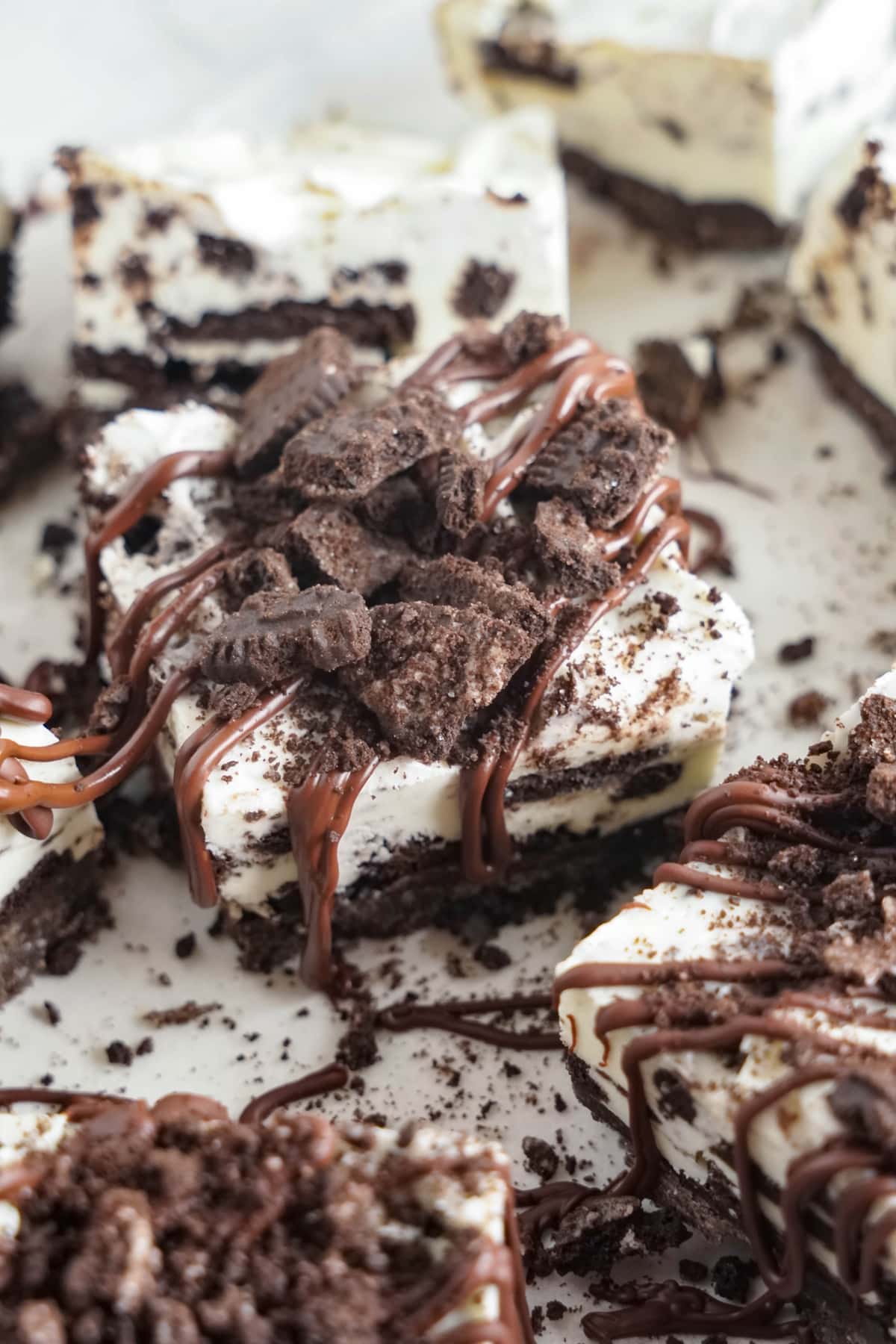 oreo cheesecake bar topped with oreo pieces and chocolate drizzle