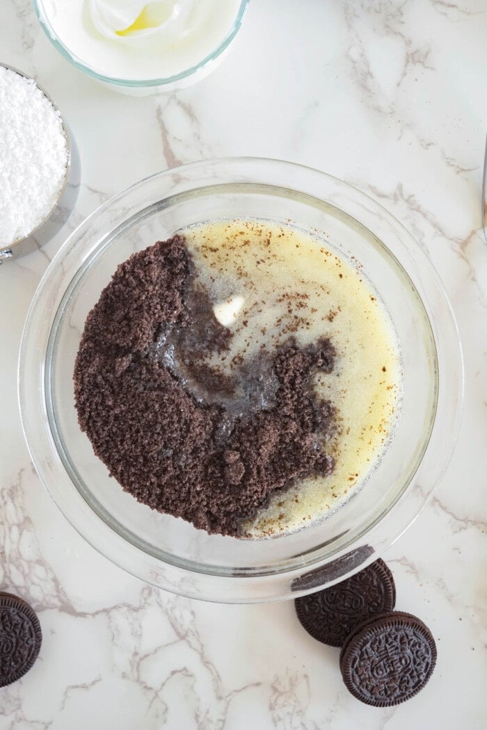 crushed oreos and melted butter in glass bowl