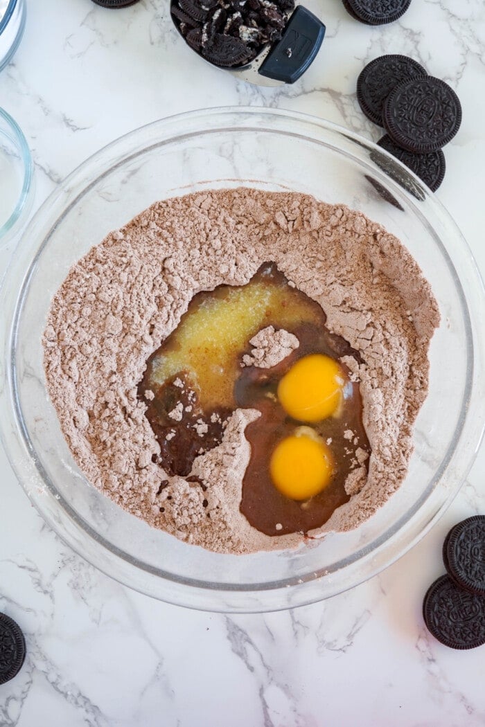 eggs in glass bowl with ingredients to make oreo stuffed chocolate cookies