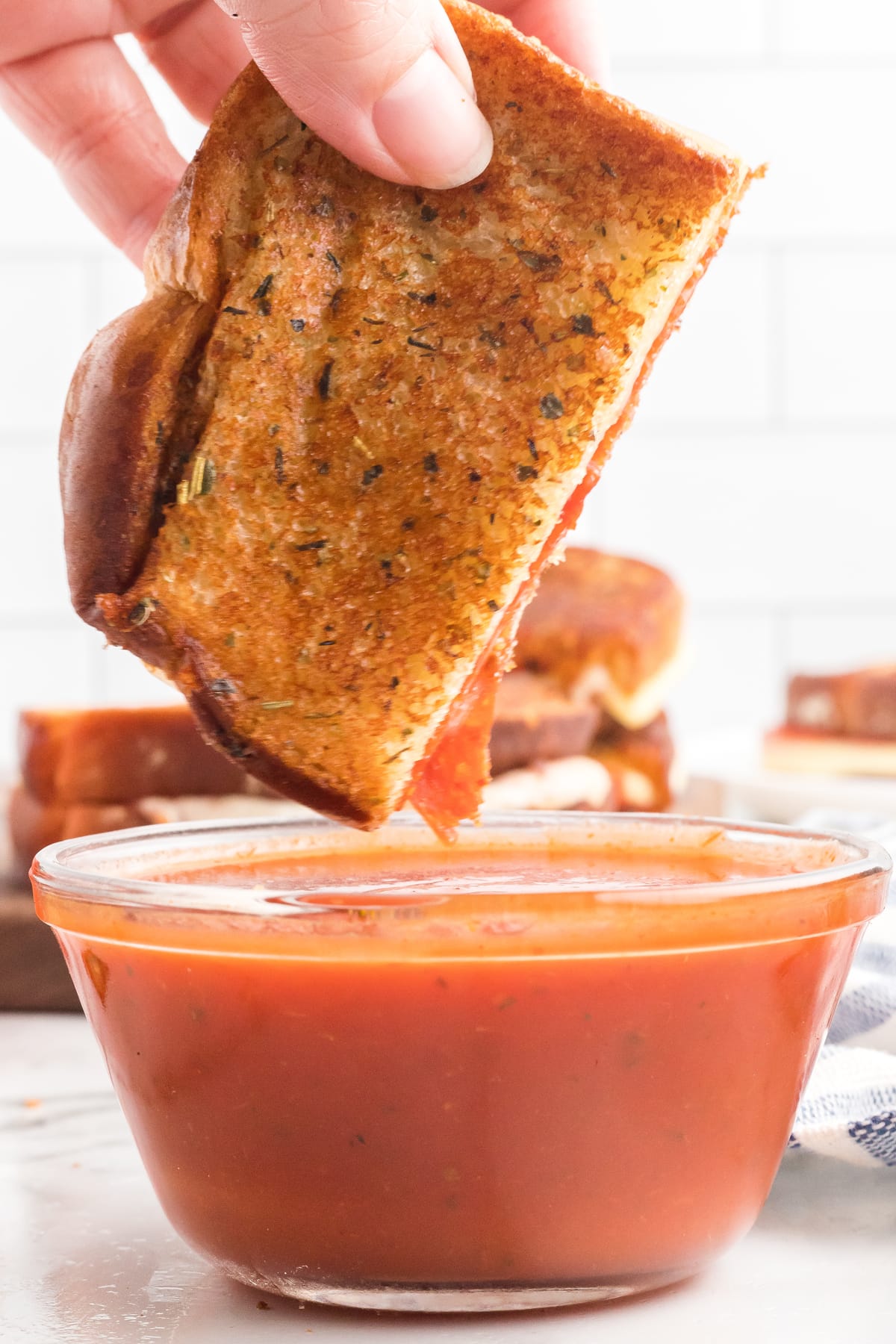 hand dipping pizza grilled cheese into pizza sauce