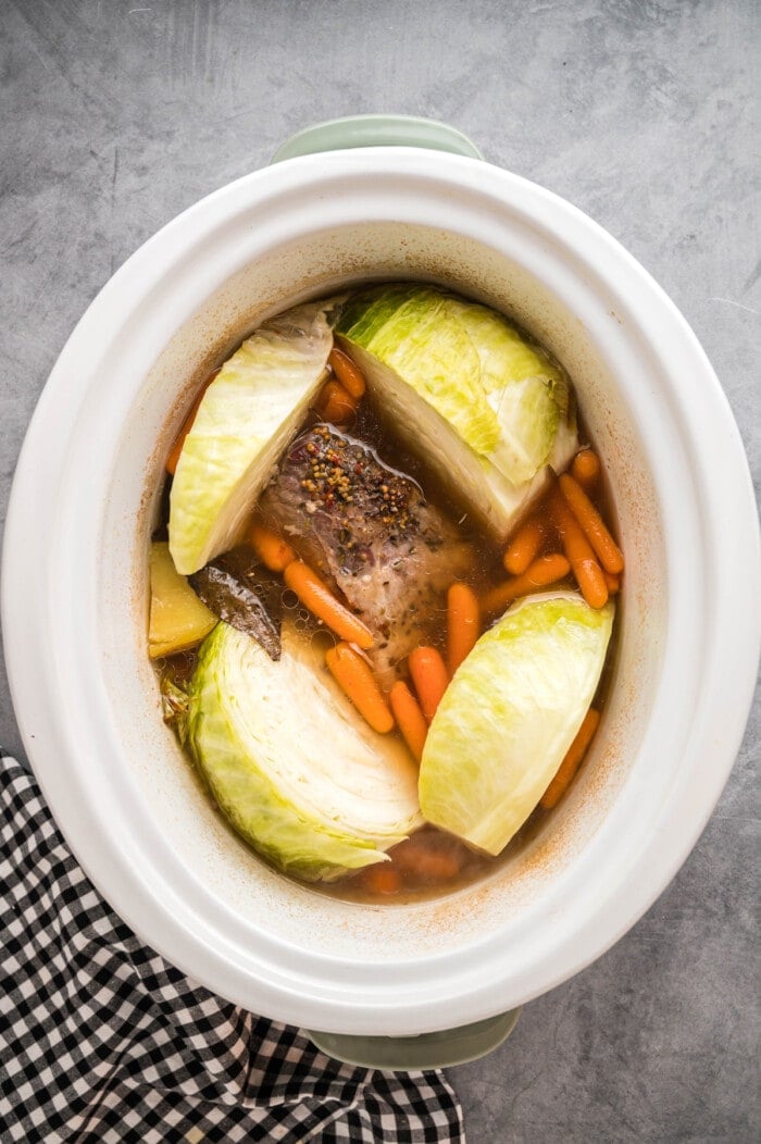 Cabbage added on top of corned beef, carrots, and potatoes in the slow cooker