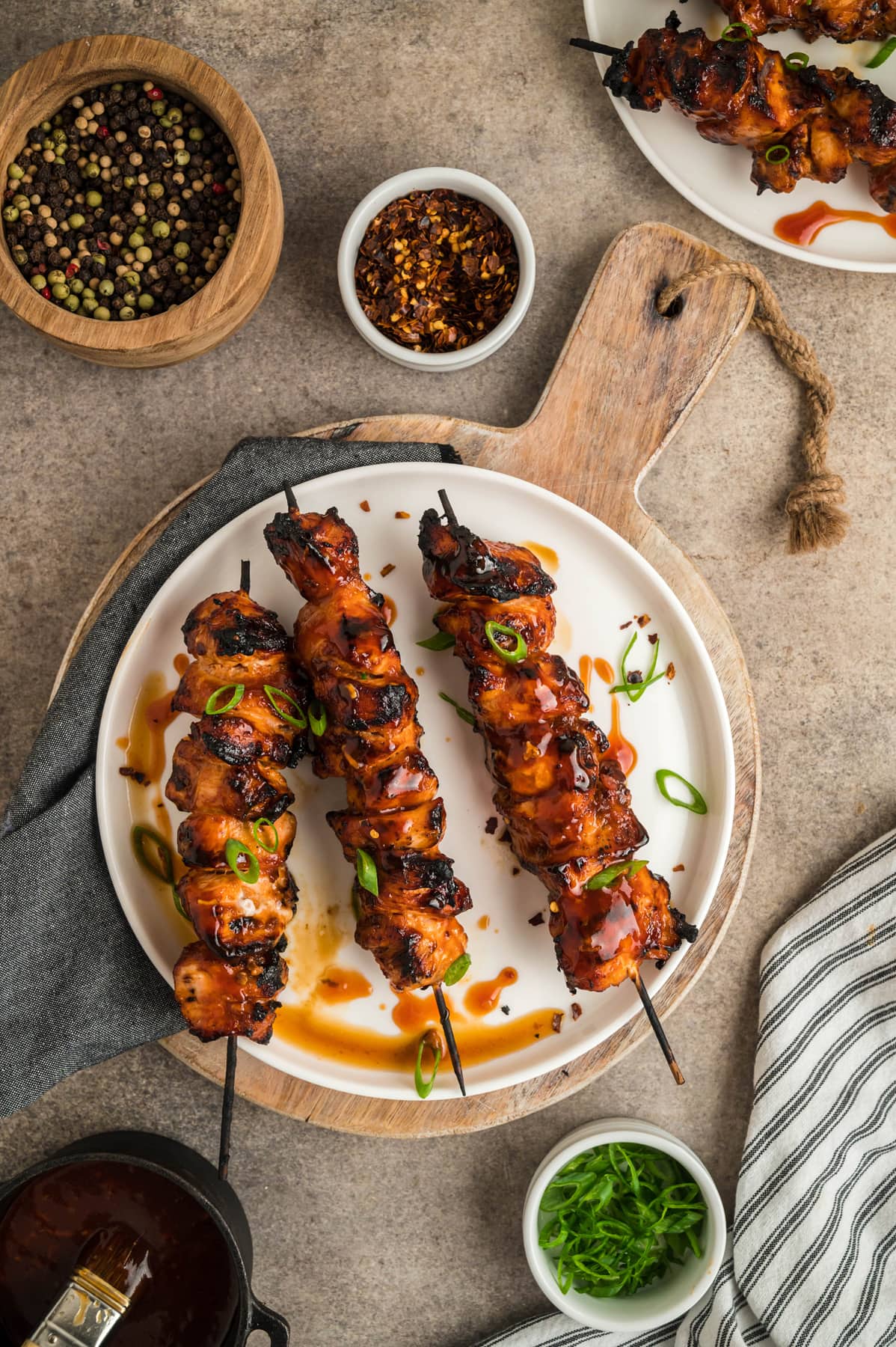 Three chicken skewers on a white plate
