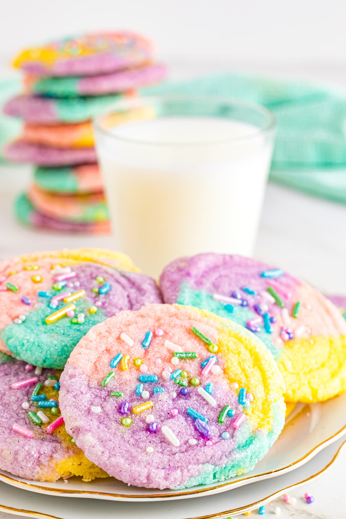 unicorn cookies on white plate with glass of milk