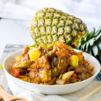 Crockpot Sweet and Sour Pork with a whole pineapple behind it.