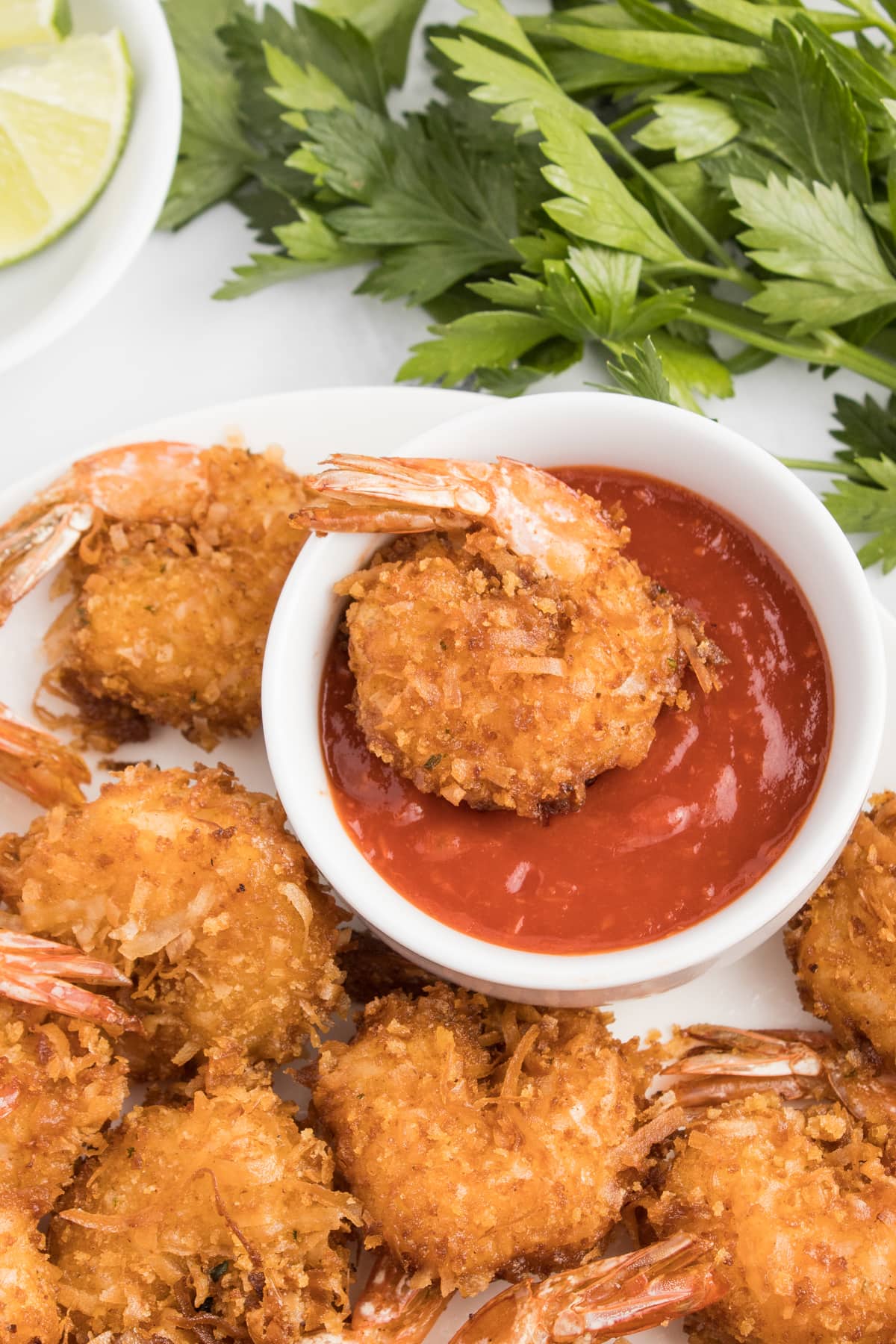 A coconut shrimp dipped into a dish of sauce