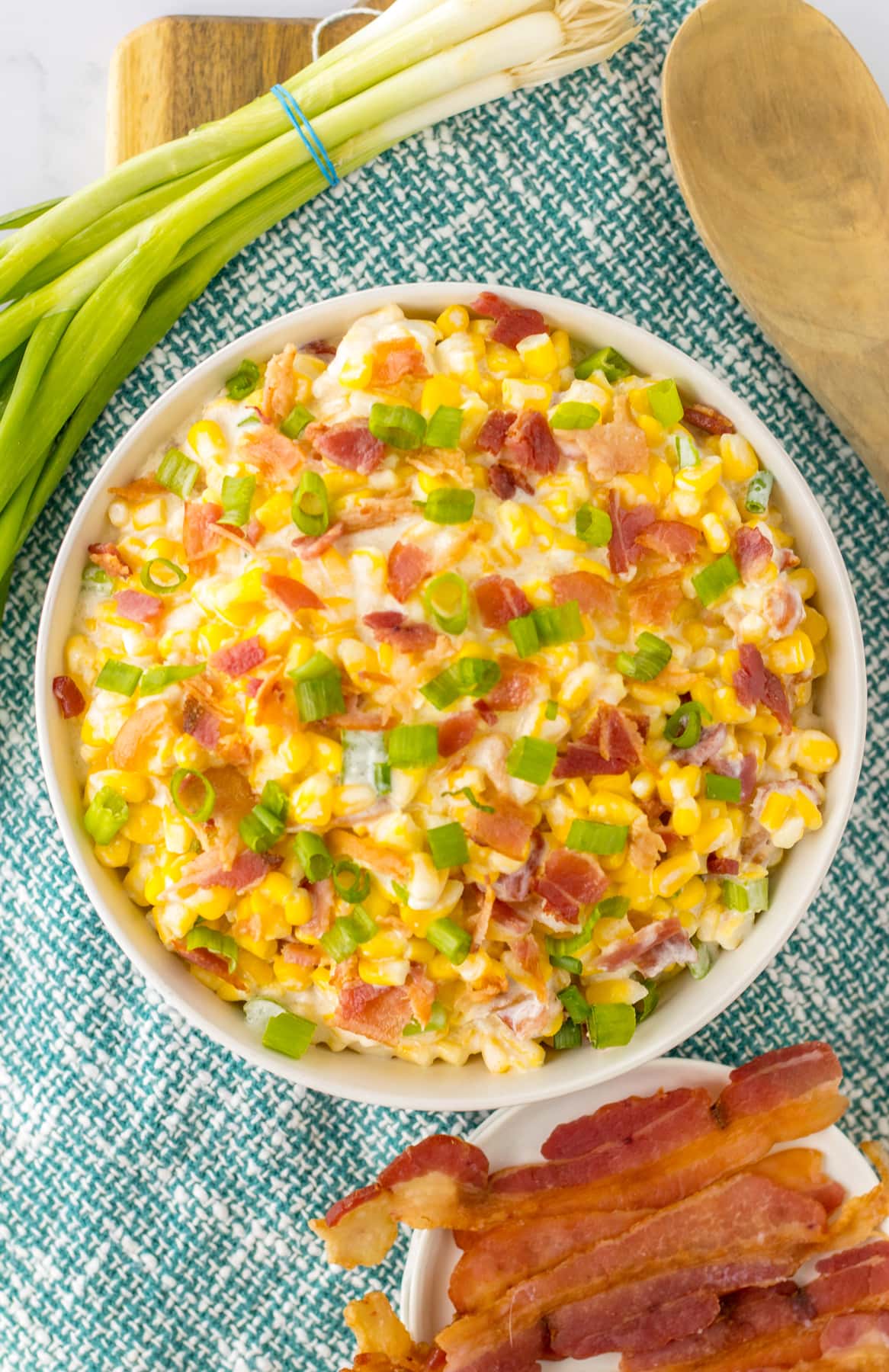 creamed corn with bacon and green onions in white bowl