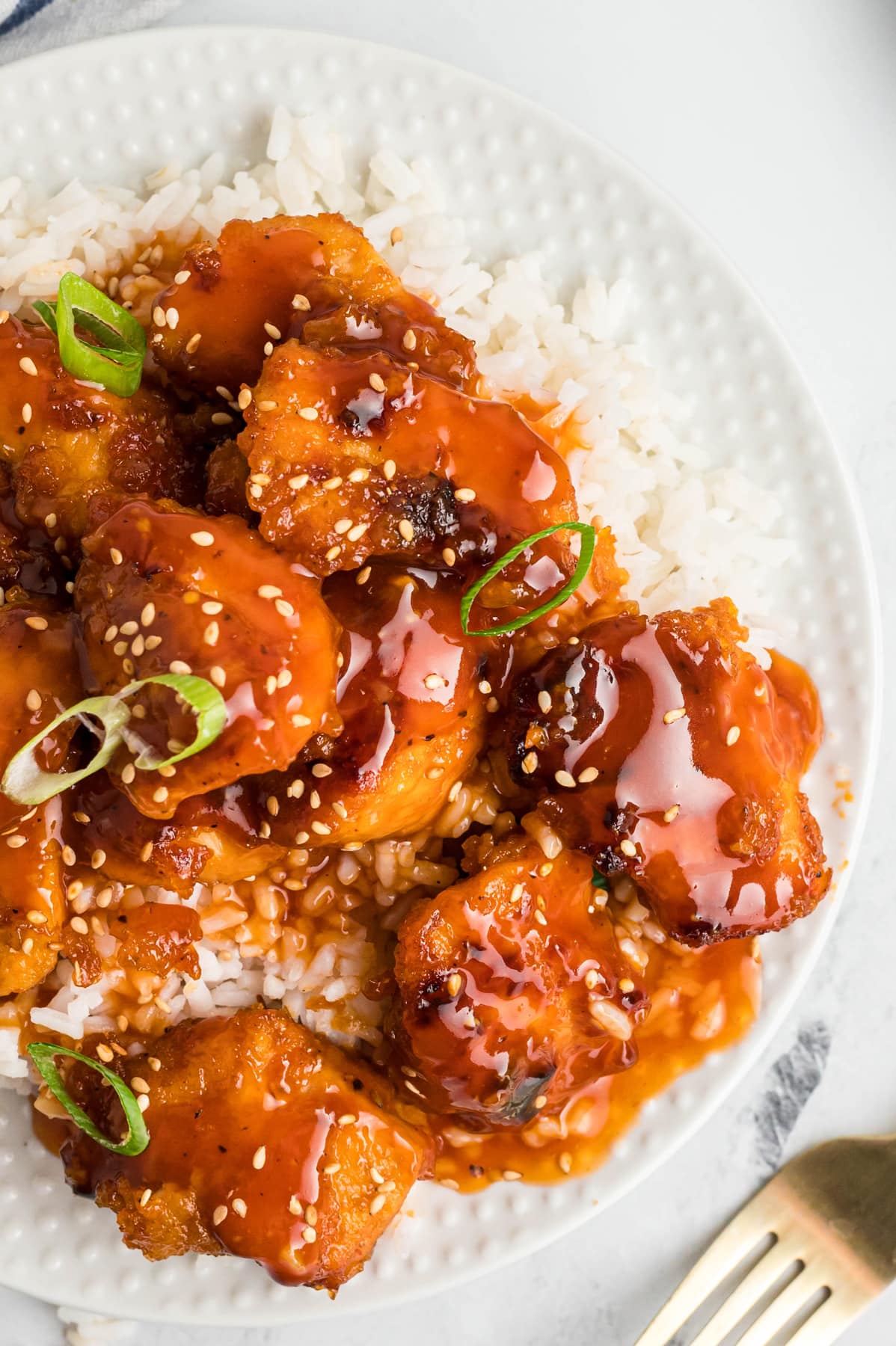 Overhead view of sweet and sour chicken over rice on a plate