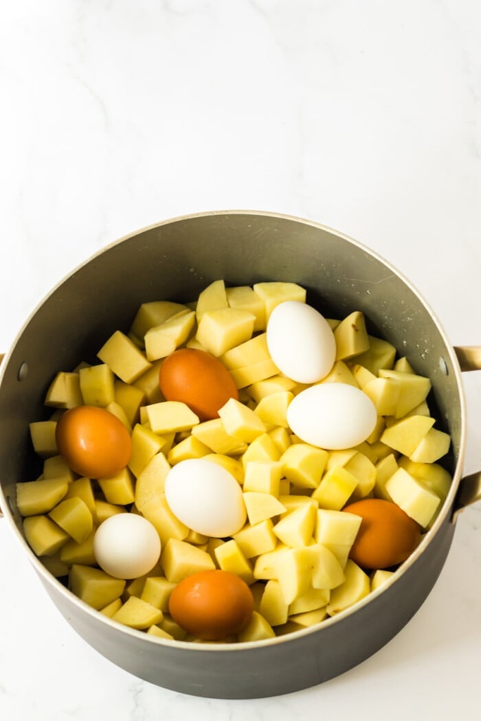 Boiled diced potatoes and hard boiled eggs in a pot.