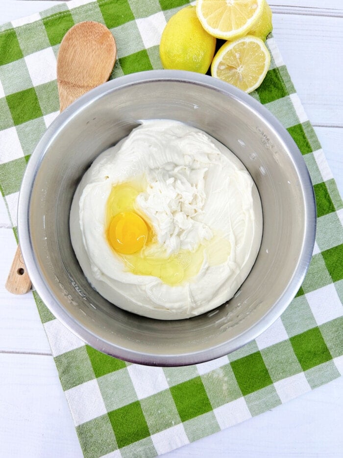 lemon cheesecake ingredients in bowl with egg