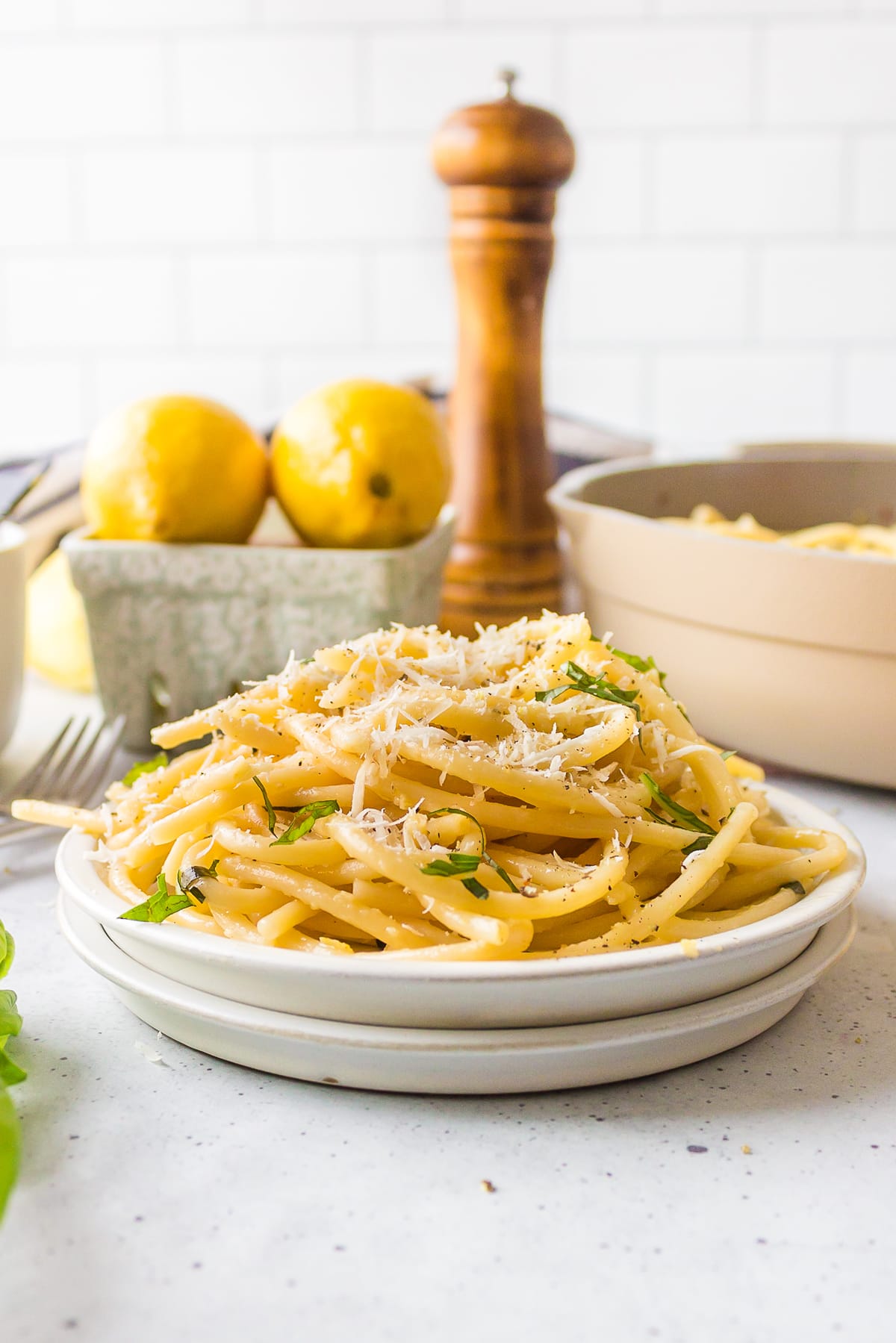lemon garlic pasta on white plate with parmesan cheese and basil